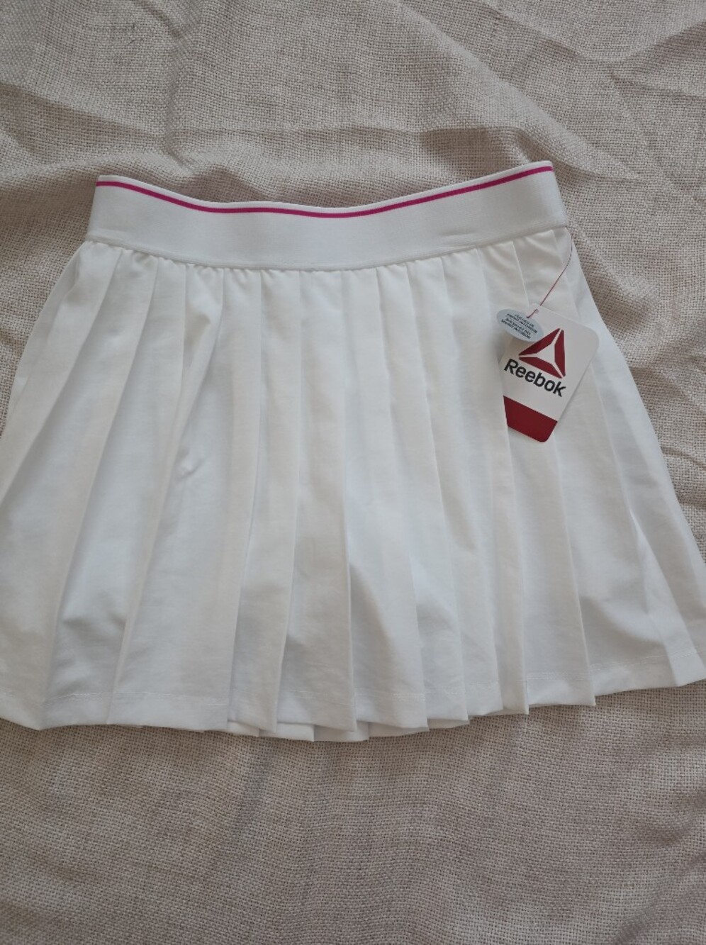 Reebok white tennis skirt features a classic pleated design with a pink accent